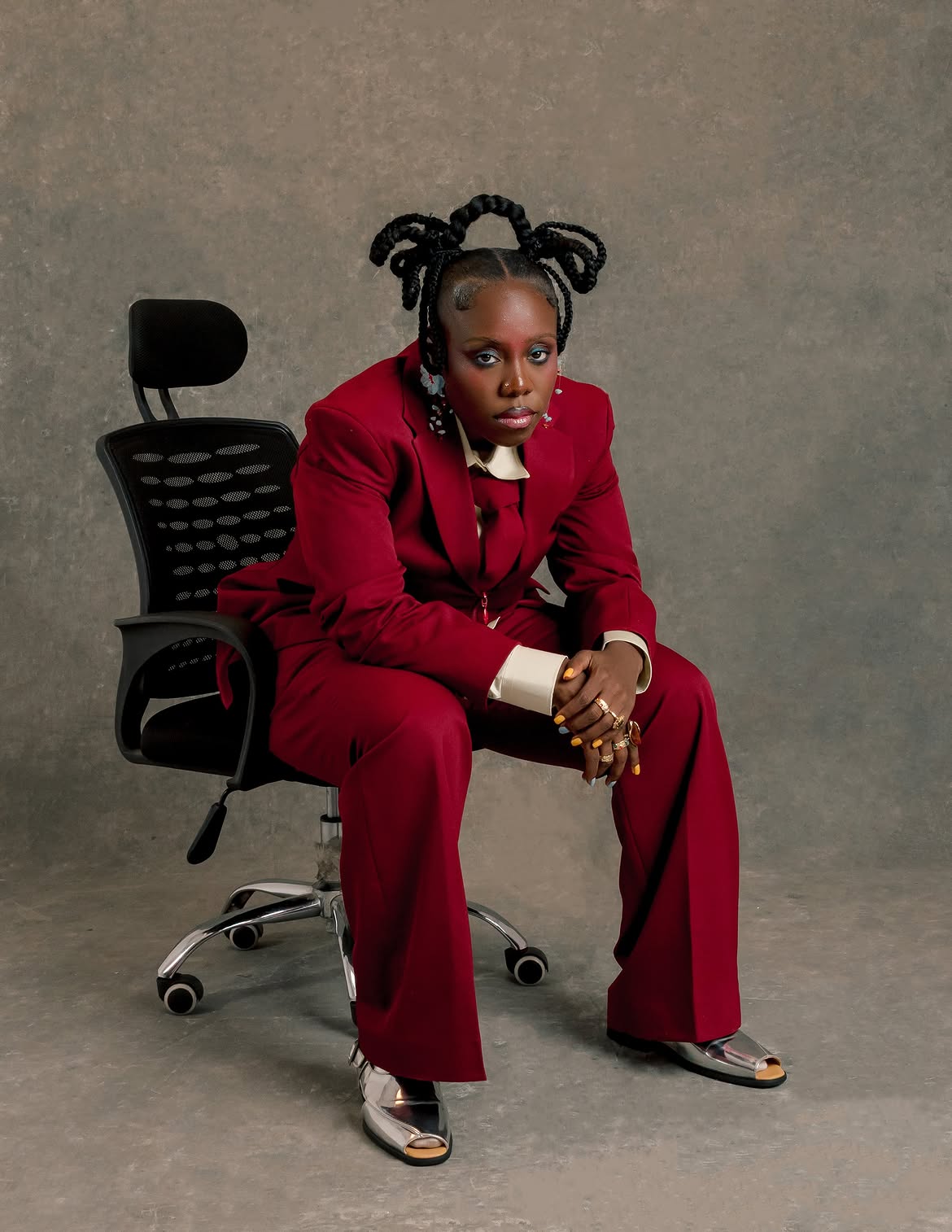 Teni wearing a crimson double-breasted suit with silver grills