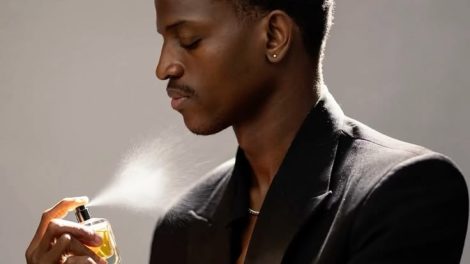 Black man applying deodorant and perfume getting ready