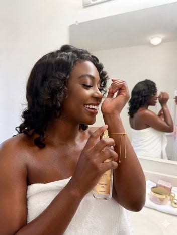 Black woman applying deodorant and perfume getting ready